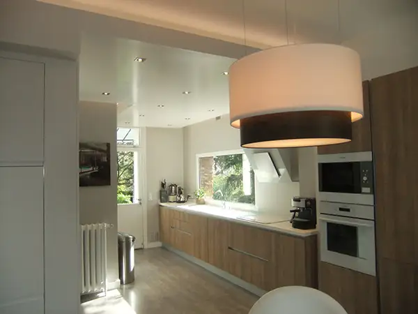 Vue perspective d'une cuisine contemporaine avec plan de travail blanc et éclairage design, projet signé Home Feeling à Montmorency