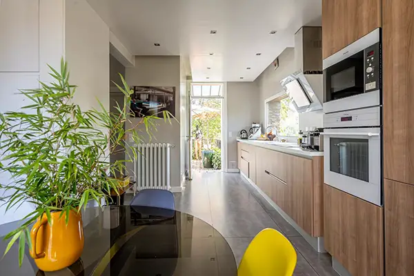 Vue perspective d'une cuisine contemporaine avec plan de travail blanc et éclairage design, projet signé Home Feeling à Montmorency