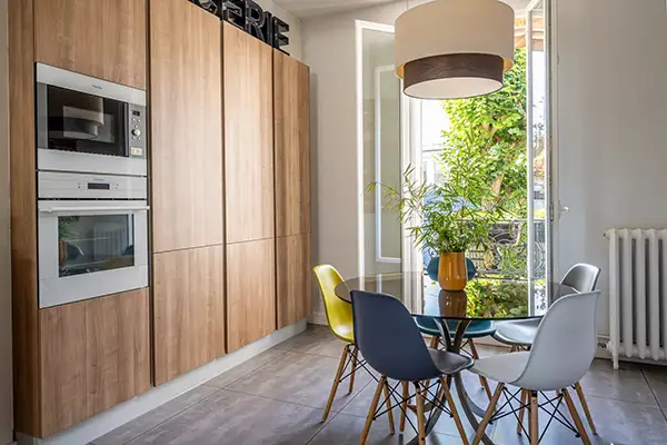 Rénovation d'une cuisine ouverte sur salle à manger dans une meulière à Montmorency par Home Feeling, avec façades bois et électroménager encastré