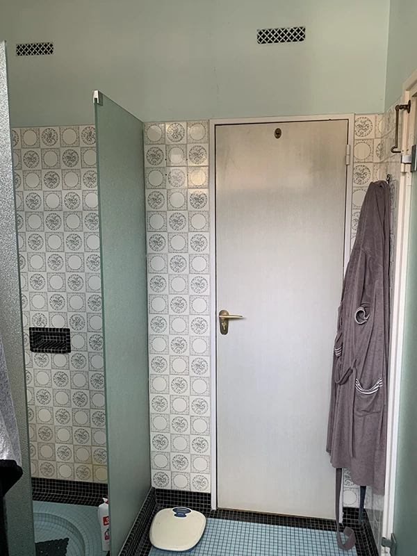 Ancienne salle d'eau des années 80 avec lavabo sur colonne bleu et carrelage vieillot avant travaux de rénovation par Home Feeling dans le Val d'Oise