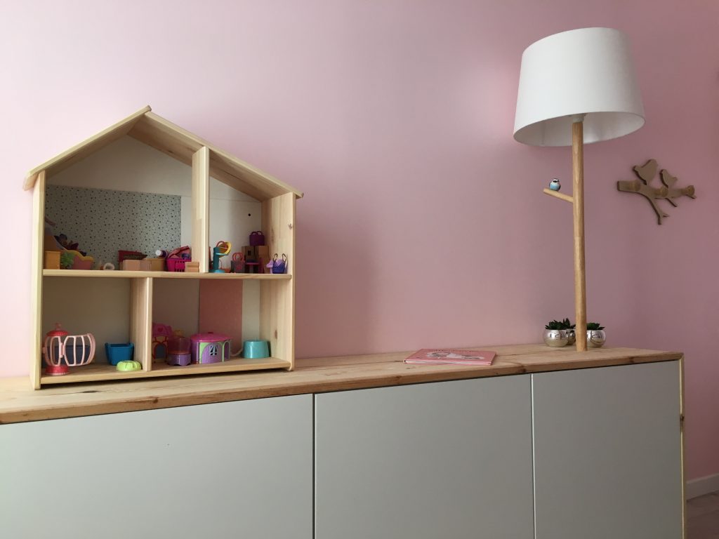 Rangement bas blanc et bois dans une chambre d'enfant avec maison de poupée et lampe en bois dans un appartement rénové par Home Feeling dans le Val d’Oise
