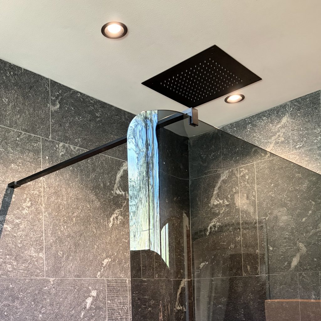Détail du plafonnier de douche noir (ciel de pluie) et spots encastrés dans une salle d'eau rénovée par Home Feeling à Pontoise