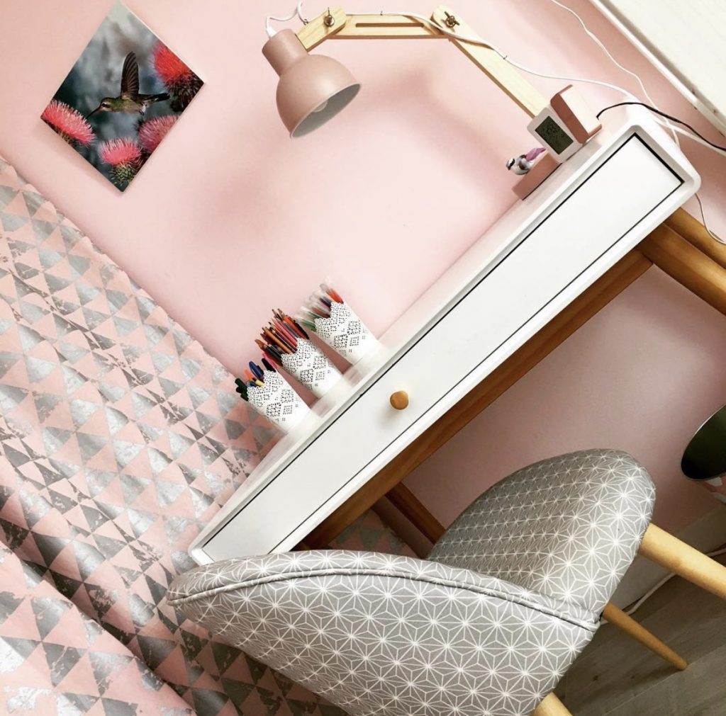 Petit bureau d'enfant blanc sur fond de mur rose poudré avec fauteuil à pois et accessoires déco dans un appartement rénové par Home Feeling dans le Val d’Oise